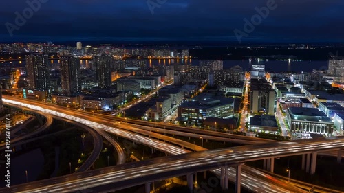 A cinematic aerial drone shot of a dense modern city at dusk, resembling New York City. Skyscrapers glow with warm office lights