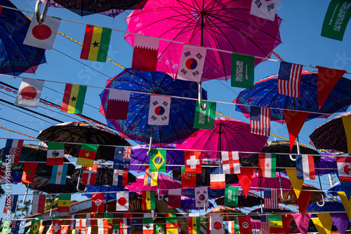 A vibrant display of colorful umbrellas suspended overhead on Isla Bastimentos, creating a lively canopy above a tropical street scene. 