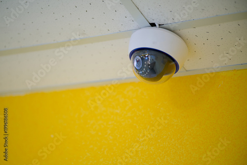 Modern rotating security camera installed on a drop ceiling inside a public building. Equipment for monitoring, video surveillance and property protection. Photo