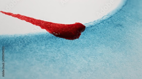 Vibrant red pigment bleeds across textured blue watercolor wash on white paper