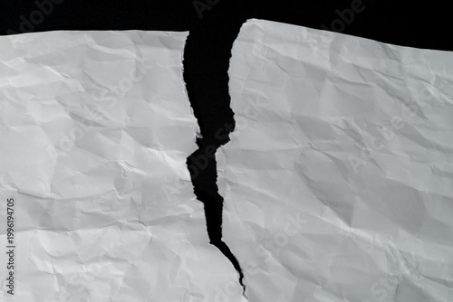 Fotografie White paper torn in half on a contrasting black background
