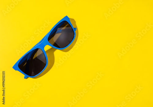 Blue sunglasses on a bright yellow background with dark lenses and a stylish frame