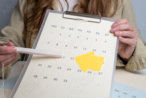 Hands placing yellow speech bubble stickers in notebook over calendars. Creative brainstorming concept. 
