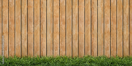 Vintage brown wooden plank fence with a rough timber texture and natural green grass creates a weathered backdrop pattern for this old hardwood surface material