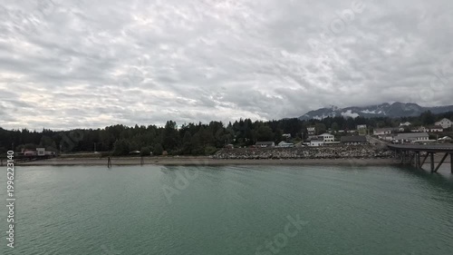 Haines - Alaska - USA - April 21, 2024 - Overview of coastal waters beside the town. The trees line the coast near the water. Houses and buildings are viewed along the coast with mountains in the back