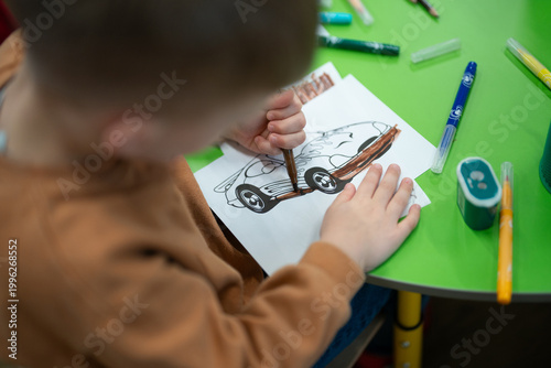 Cuadro en lienzo Child using a brown marker to color a car drawing