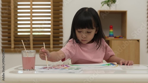 happy preschool child girl painting with watercolor on paper at home