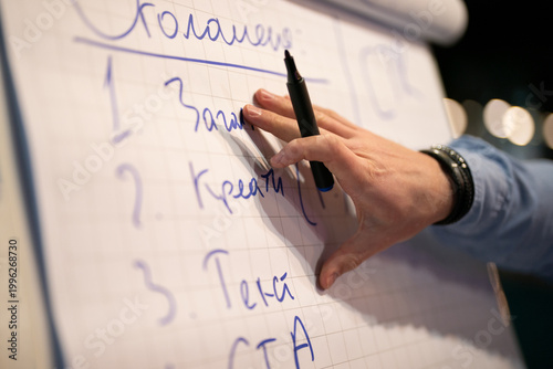 Tableau sur toile Close-up of a person writing numbers on a flipchart with a black marker