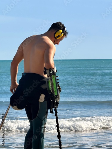 Man metal detecting on beach with ocean waves and outdoor lifestyle