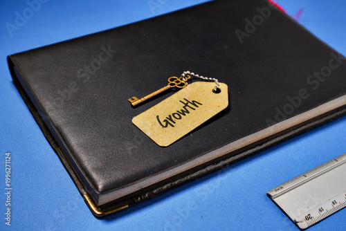 A vintage key with a tag that says Growth lies on a notebook, symbolizing business success and development.