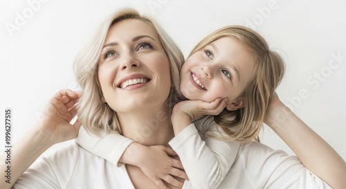Happy mother and daughter smiling and looking up with their arms around each other in a studio setting.
