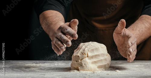 Quadro su tela Baker hands shaping dough with flour dust on dark background artisan bread makin