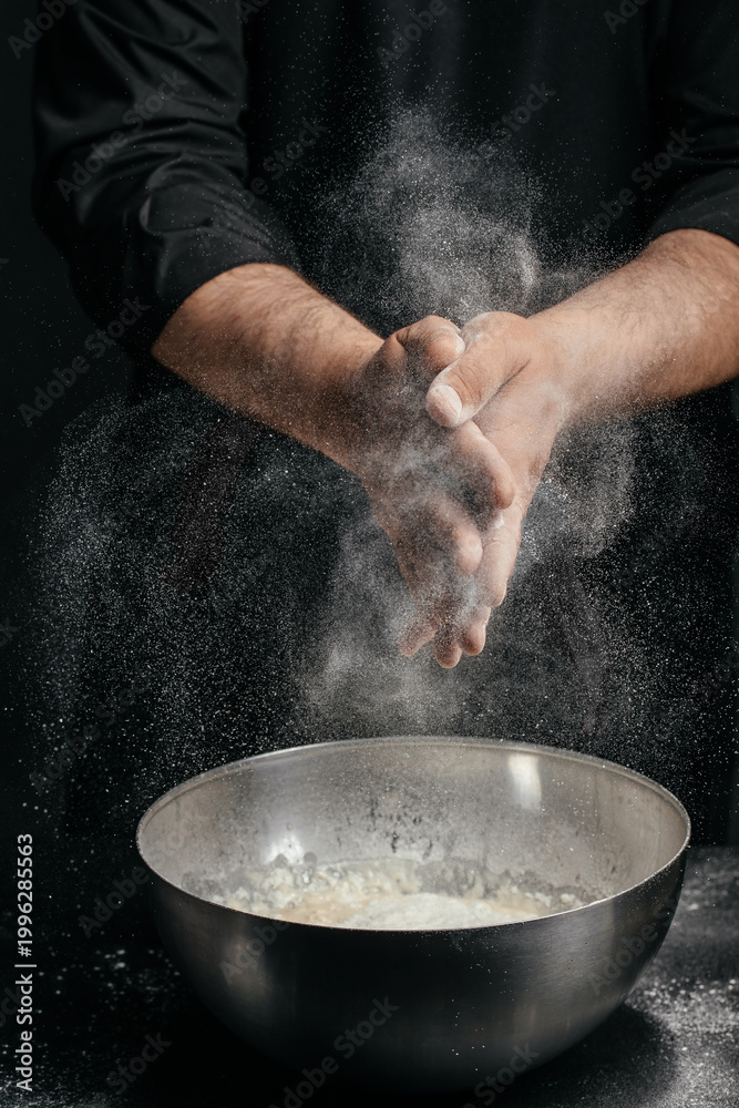 Fototapeta premium Chef clapping hands with flour explosion over bowl dramatic baking action shot