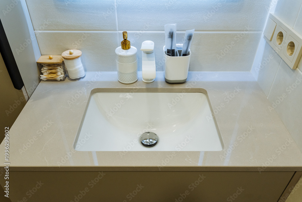 Fototapeta premium Cosmetic Area With Essential Accessories. Streamlined Wash Basin With Grooming Essentials Displayed Neatly. Tidy Personal Care Station Featuring Cleaning Products And Lighting Accents
