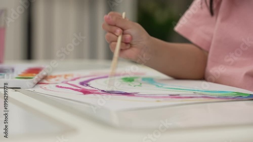 close up of preschool child girl painting on paper with watercolor in pan at home