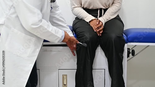 1080p 60fps horizontal video of a doctor checking a patient's reflexes with his percussion hammer, both of Latin origin
