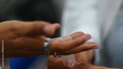 1080p 60fps horizontal video of a doctor treating a finger wound with tape for his patient in his office, both of Latino origin
