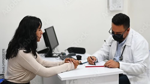 1080p 60fps horizontal video of a doctor writing a prescription to his patient in his office, both of Latino origin
