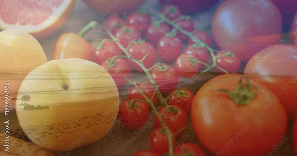 Fototapeta premium Showing double-exposed fruit blending on wood tabletop, with vine of cherry tomatoes and sunset sea