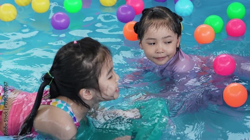 slow motion of happy preschool child girl playing together with her sister in outdoor portable swimming pool in backyard at home