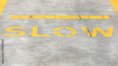 Принти на полотні Yellow painted slow road marking on a grey asphalt road surface indicating a tra