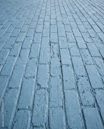 Light blue painted brick wall background with angled perspective. Rough textured urban masonry surface showing depth, leading lines, and blank copy space for design.