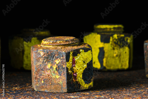 Close-up of thick old bolts with nuts on a rusty steel surface, in dark industrial environment