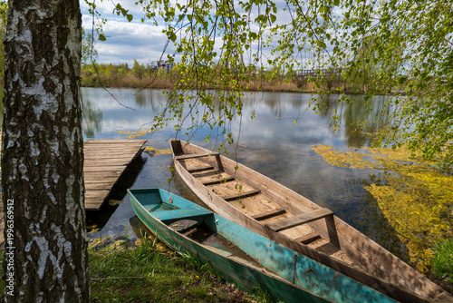 Φωτογραφία Two wooden boats are nestled by the calm lake, surrounded by lush greenery and r