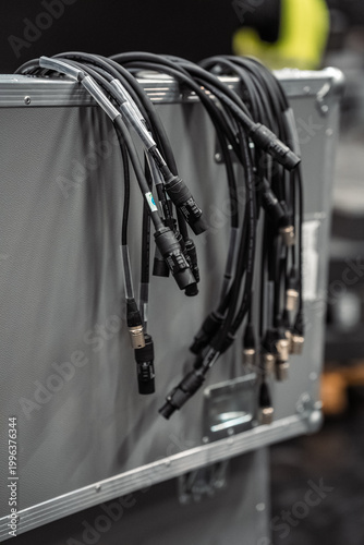 Fotografie XLR audio and power cables draped over silver flight case in backstage event pro