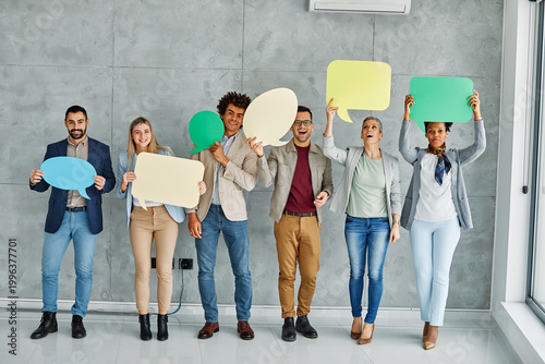 Portrait of a group of young business people in office. Speech bubble, team and comment by business people holding sign, news and voice icon feeling excited on social media. Group, opinion and poll by