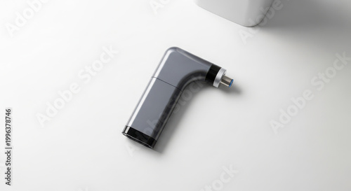 Sleek, ergonomic dental handpiece with a grey finish and blue tip, isolated on a smooth white surface, representing advanced dental tools and procedures.