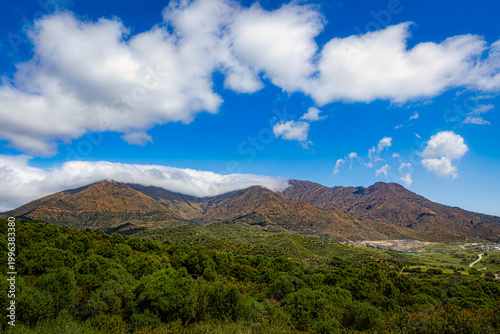 Paisaje de montaña mística en Sierra Crestellina Casares con nubes bajas abrazando la cumbre bajo cielo azul concepto de libertad esperanza purificación y naturaleza salvaje mística en horizonte infin