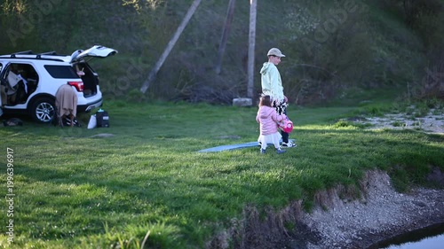 Joyful Family Moments by the River: Kids Explore Nature and Play with Flowers During a Relaxing Outdoor Excursion