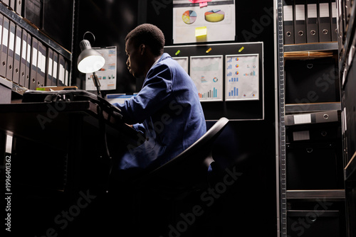 Cuadro en lienzo African american police officer working at crime case late at night, sitting at desk in police station