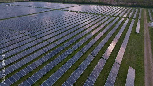 Aerial view of a large solar farm with rows of photovoltaic panels on green grass during sunset in Indianapolis, Indiana, United States.