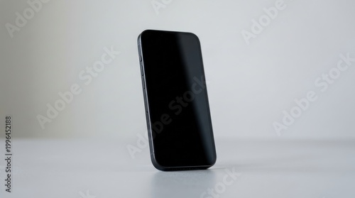 A black smartphone standing upright on a white surface.