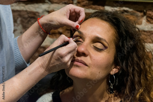 Make-up artist painting woman's eyes