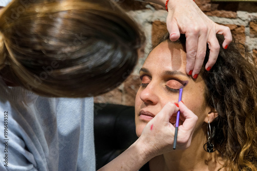 Make-up artist painting woman's eyes