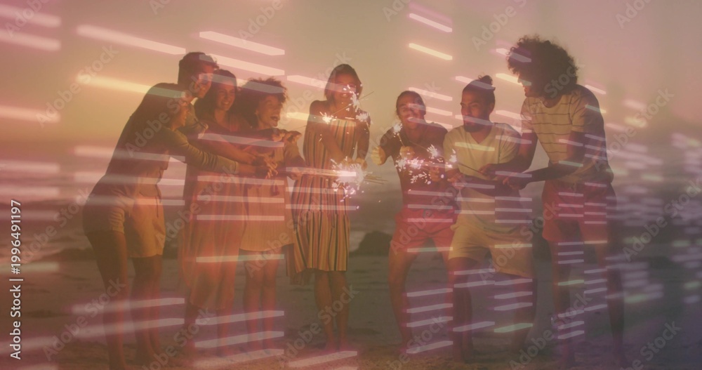 Obraz premium Waving sparklers, eight adults in summer clothes posing on beach at sunset, with streaked light