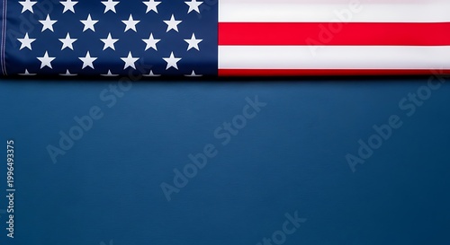 A folded american flag positioned at the top of a deep blue background for patriotic composition