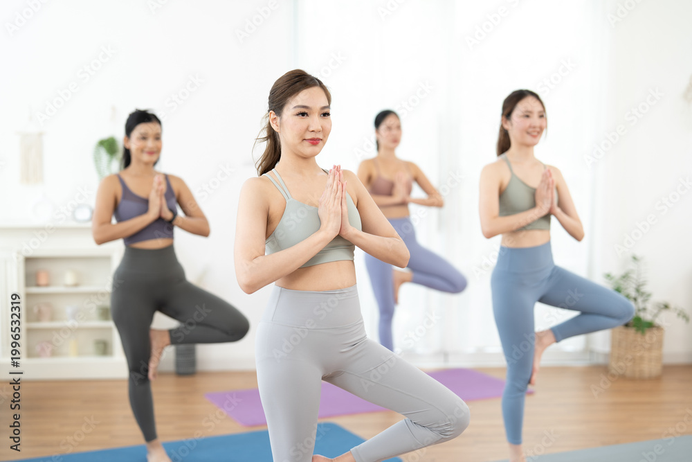 Obraz premium Wellness pilates and yoga, yoga class group practicing balance pose in bright studio calm wellness exercise