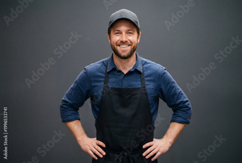 Smiling male service worker in black apron and cap