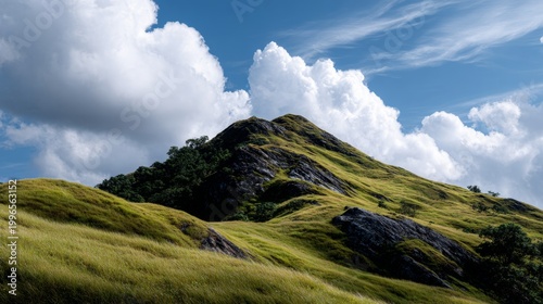 Scenic green mountain peak under bright blue sky with fluffy white clouds, landscape of grassy hills.