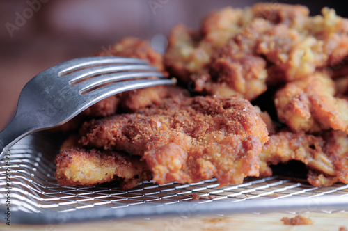 Milanesas de pollo pescado o camarones empanizados o carne de res en una rejilla de aluminio con un tenedor al lado, vista lateral con acercamiento o macro.