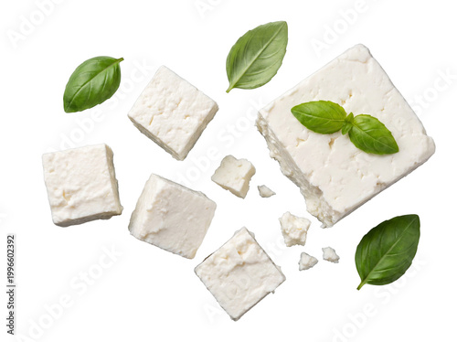 Tableau sur toile White feta cheese cubes, some crumbled, with fresh aromatic basil leaves scattered on a transparent background