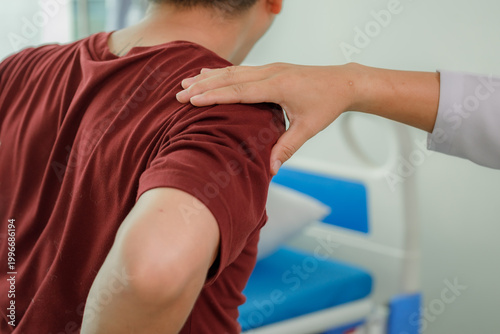 Fotografija Specialist using trigger point massage on a patient's shoulders and upper back