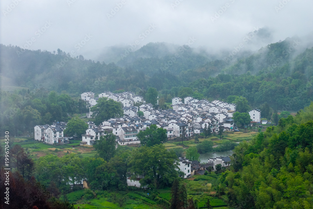 Obraz premium Traditional white houses of Huizhou Ancient City stand in the scenic green mountains of She County in Anhui province China during a beautiful morning with soft mist covering the landscape