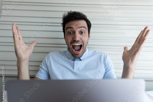 Konstfotografi Celebrating man raising his arm rejoicing over positive results on his laptop