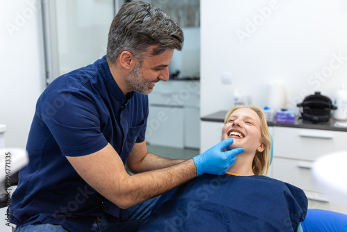Tableau sur toile Male dentist examining teeth of young blonde female patient
