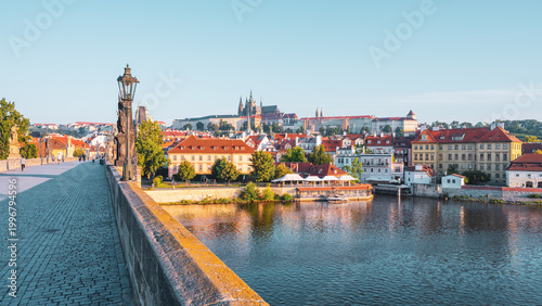 Foto A stunning view showcases the historic Charles Bridge leading to Prague Castle, featuring cobblestone pathways and charming rooftops under a clear blue sky